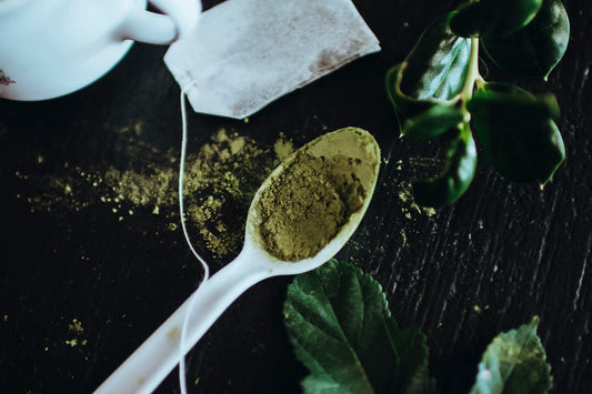 Matcha powder vs green tea shown with powdered tea, a tea bag, and fresh leaves on a dark table