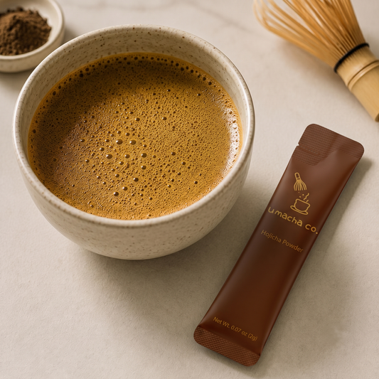 Prepared hojicha in a ceramic bowl beside a bamboo whisk and single-serve hojicha stick