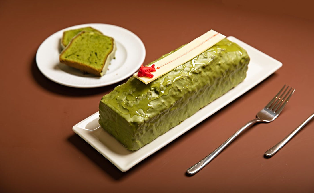 Glazed matcha loaf cake on a white platter with two slices on a separate plate