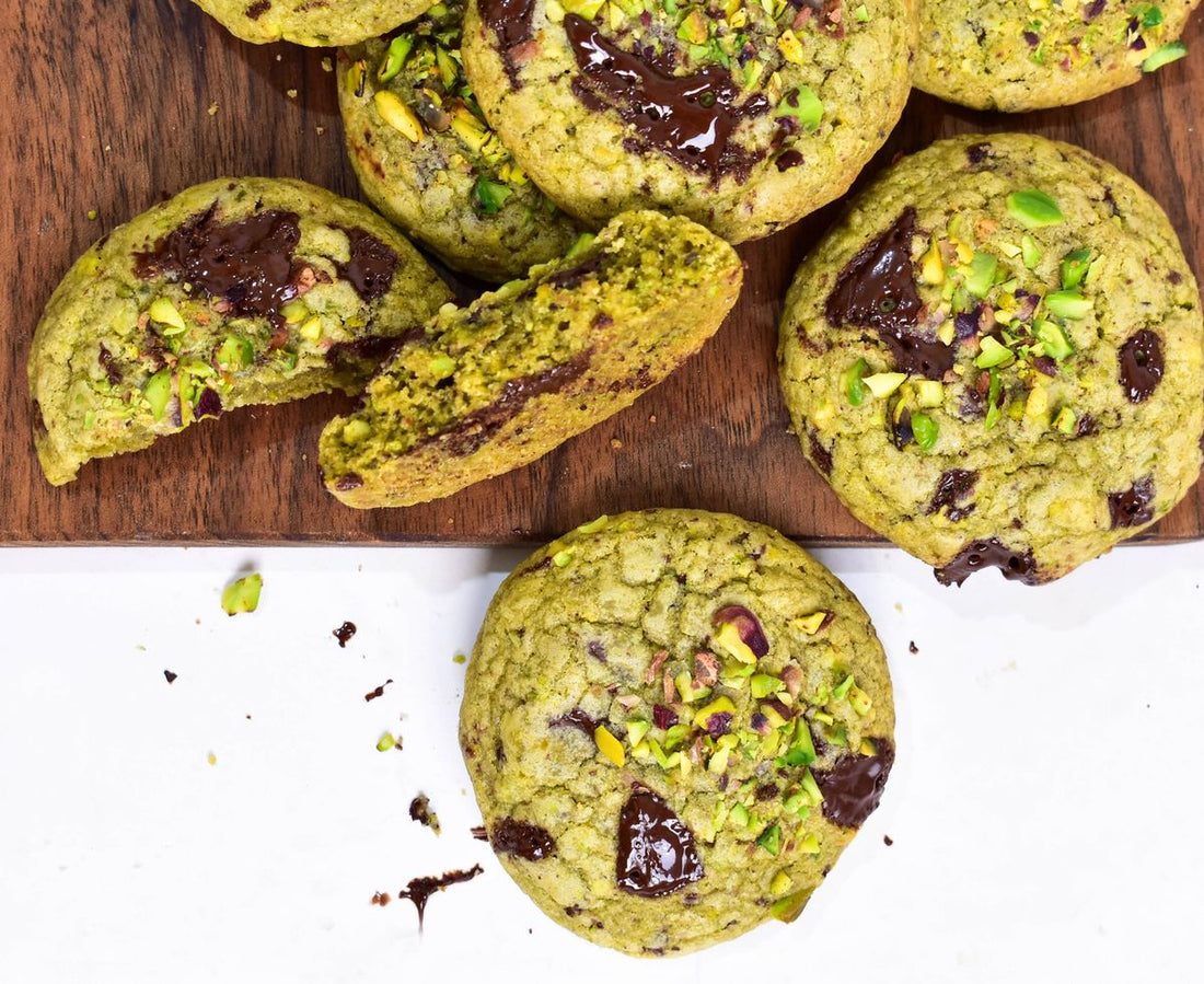 Matcha cookies recipe with chocolate pieces and chopped pistachios on a wooden board