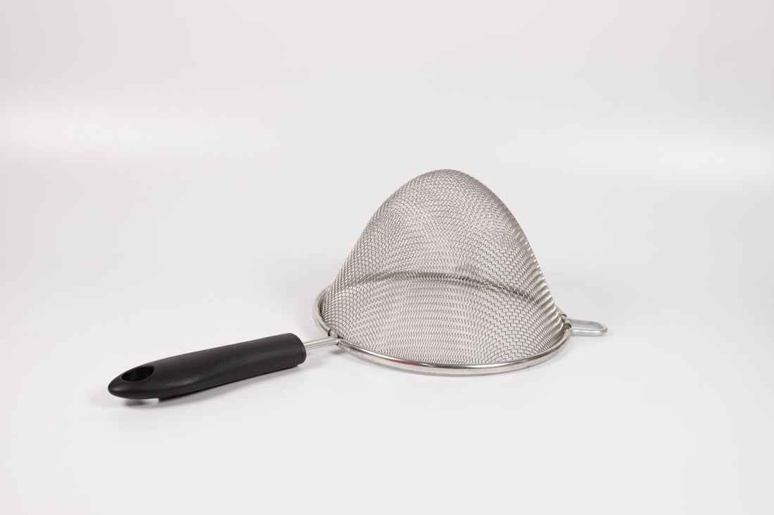 Fine mesh strainer with a black handle resting upside down on a white background