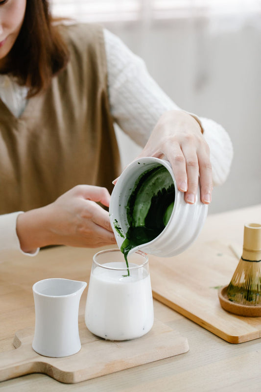 Pouring green matcha into milk while testing the best milk for matcha